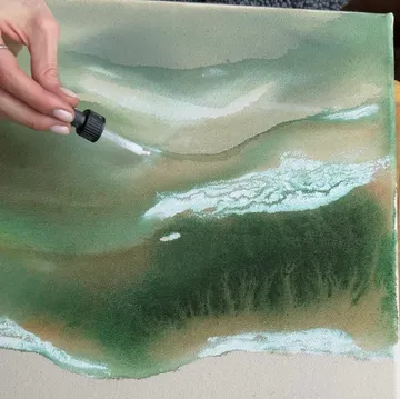 Hand mit Pipette auf abstrakter Leinwandmalerei.