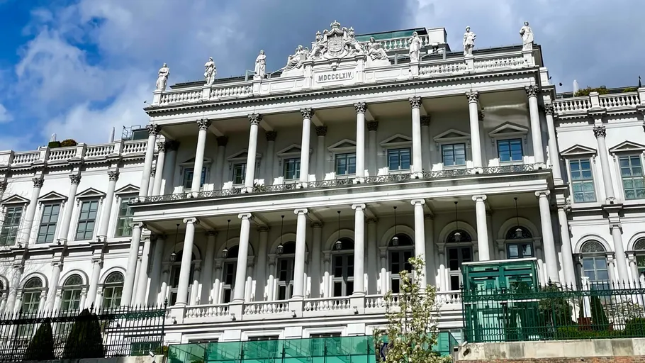 Historisches Gebäude mit Säulen, Statuen und Wolkenhimmel.