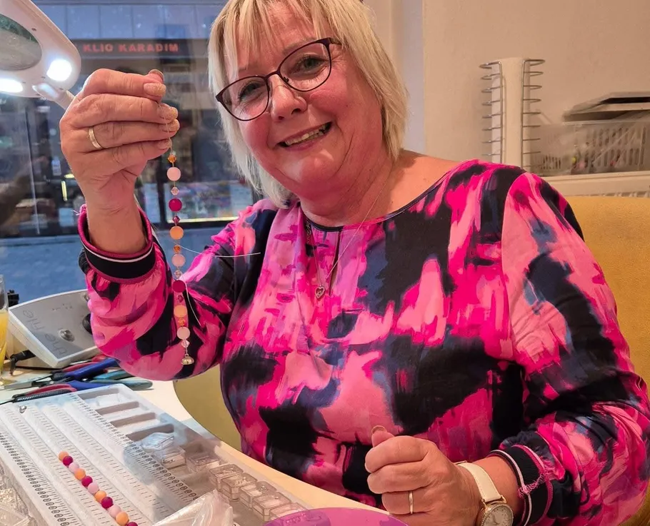 Woman in pink holding beaded bracelet.