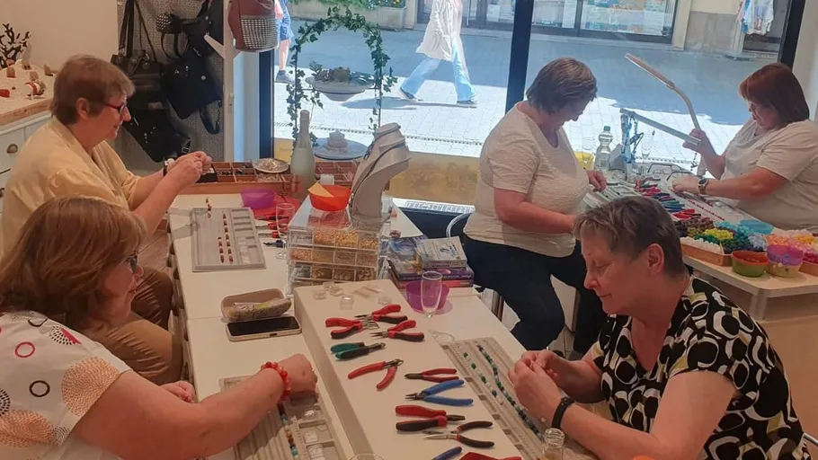 Frauen basteln Schmuck an einem Werkstatttisch.