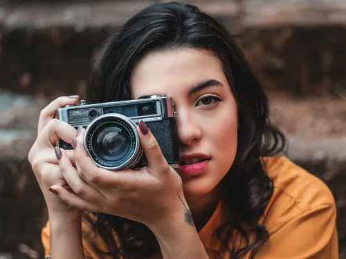 Woman holding camera, looking directly in front of stairs.