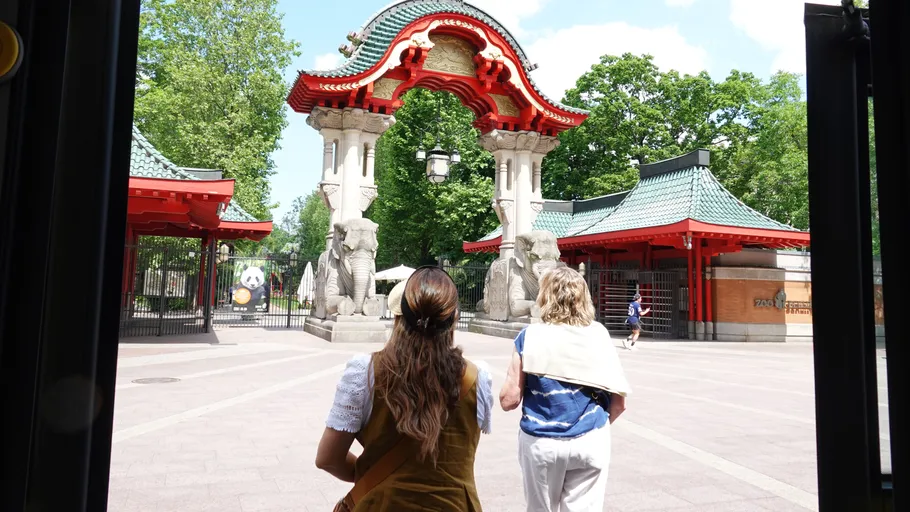 Zwei Frauen gehen zum verzierten Eingangstor.