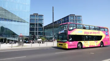 Doppeldecker-Tourbus fährt an modernen Glasgebäuden vorbei.