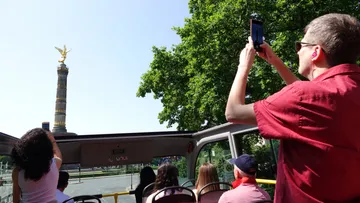 Tourists on bus photographing Berlin Victory Column.