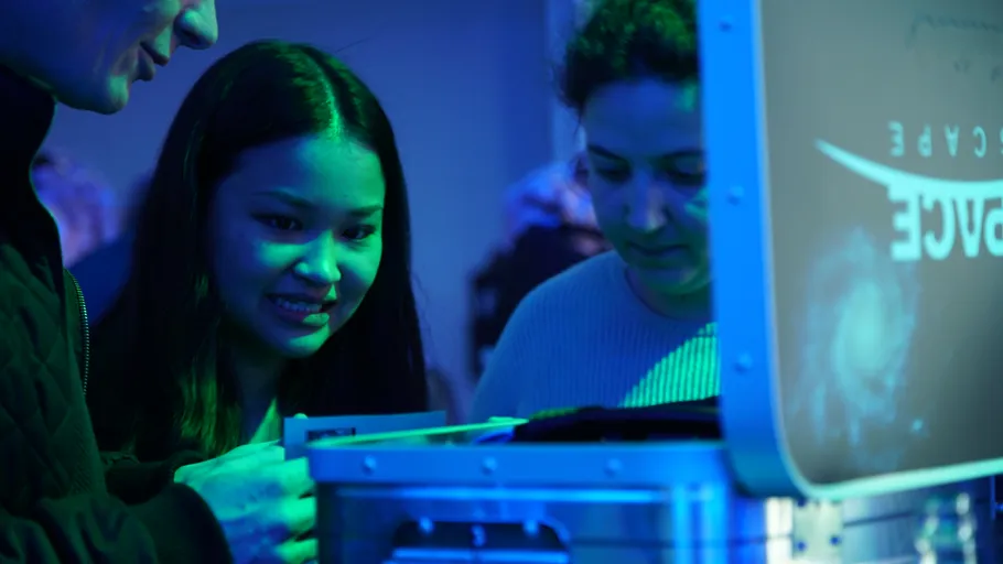 Three people examining a box in blue lighting.