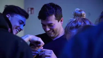 People smiling and engaging indoors with blue lighting.