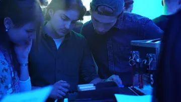 Three people focus on an escape room puzzle.