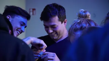 Gruppe von Menschen lächelt über etwas Kleines.