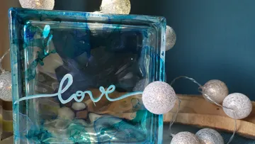 Ein blauer Glasblock zeigt das Wort `love` umgeben von Lichtern.