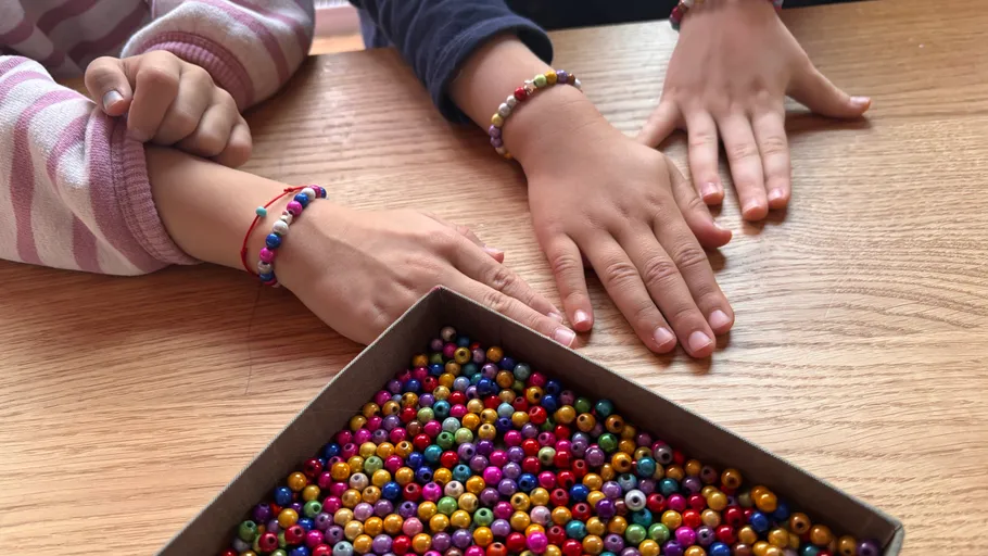 Children with beaded bracelets at a table.