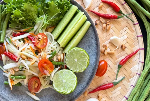 Thailändischer Salat mit Tomaten und Limette auf Teller.