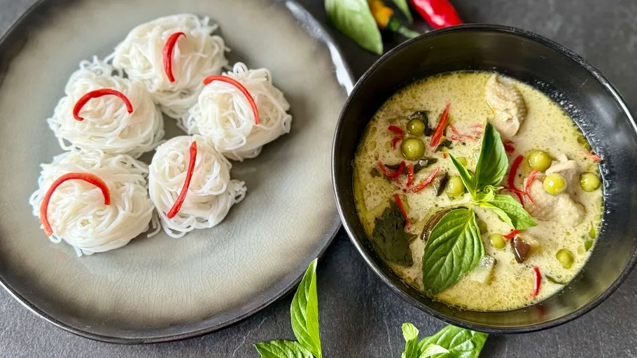 Nudeln mit roter Garnierung neben grünes Currygericht.