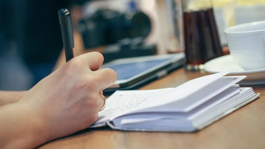 Person writing in a notebook at a table.