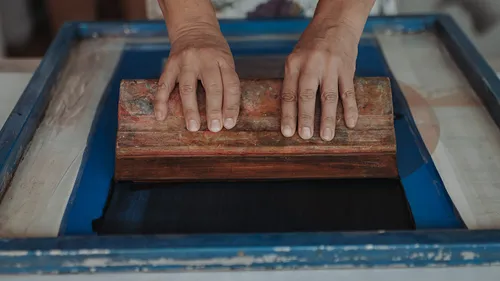 Hände benutzen Rakel im Siebdruck.