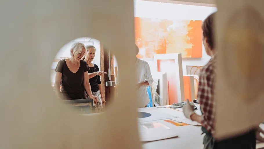 People in a studio discussing artwork.
