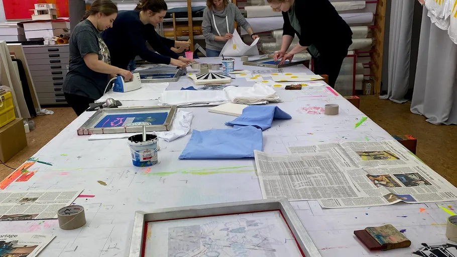 People screen printing on large table.