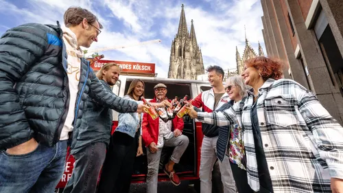 Group toasting with beer at cathedral background.