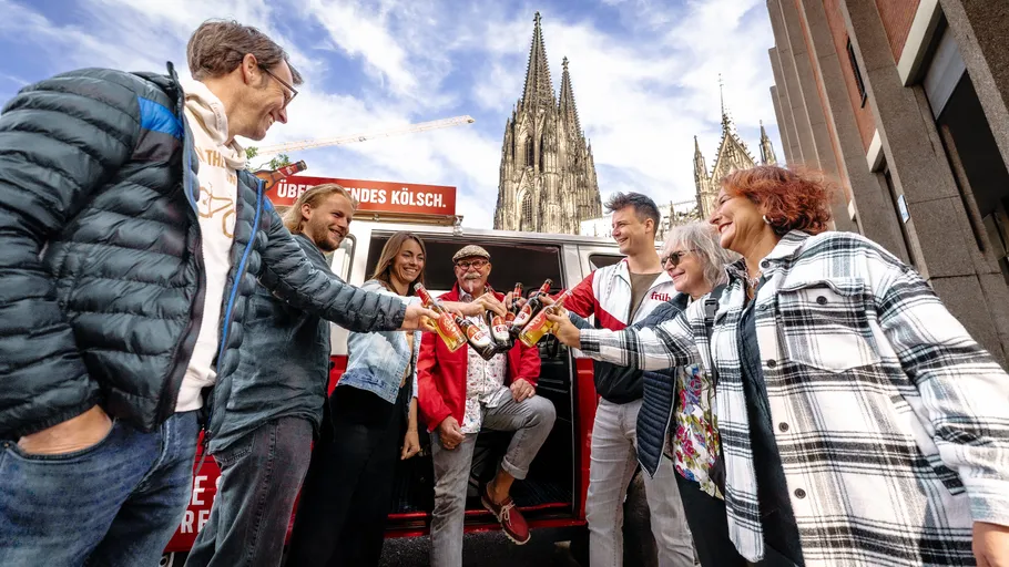 Gruppe stößt mit Bier vor Kathedralhintergrund an.