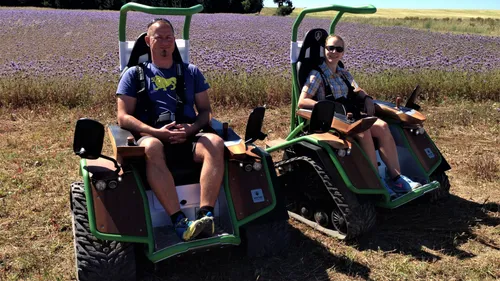 Zwei Personen auf Raupenfahrzeugen im Feld.