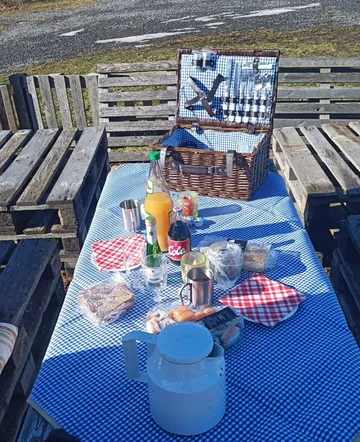 Picknicktisch mit Essen und offenem Korb.