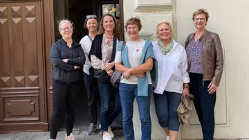 Six women smiling, standing in a row.