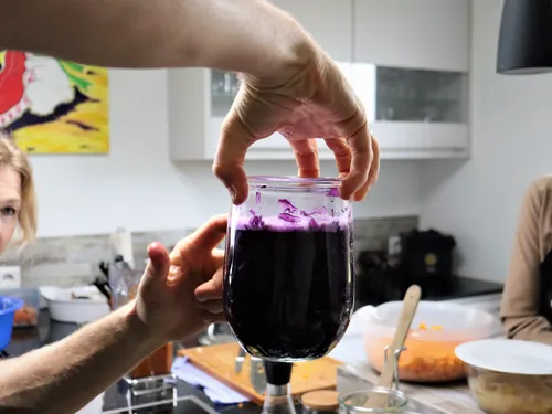A glass of purple liquid is kept in the kitchen.