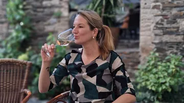 Frau trinkt Wein auf einer Terrasse.