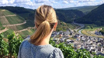 Frau blickt auf Weinberge und Dorf im Tal.
