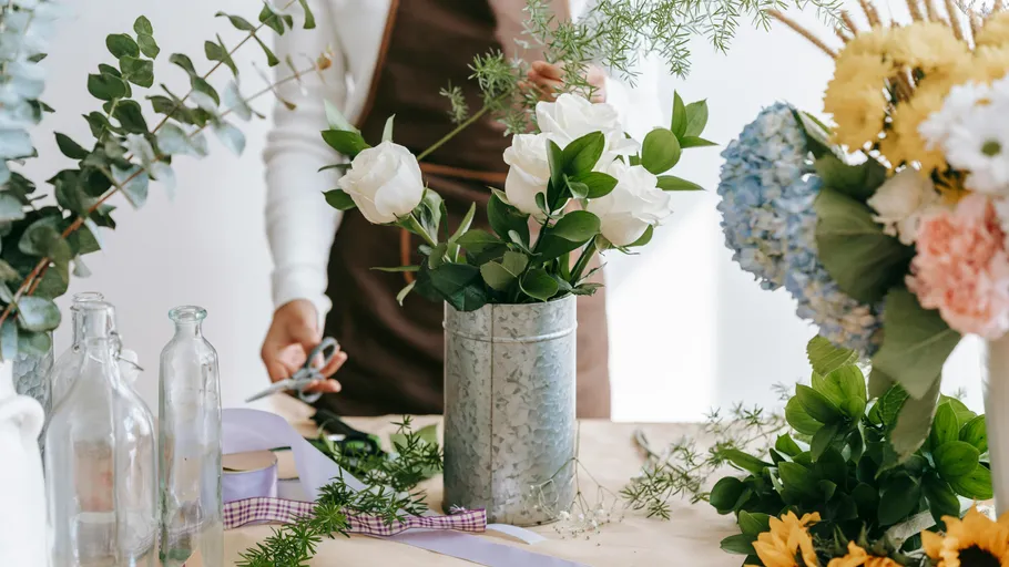 Person arranging flowers on a table.