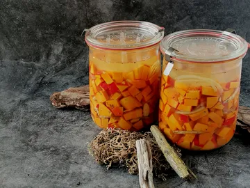 Zwei Einmachgläser mit eingelegtem Gemüse und Gewürzen.