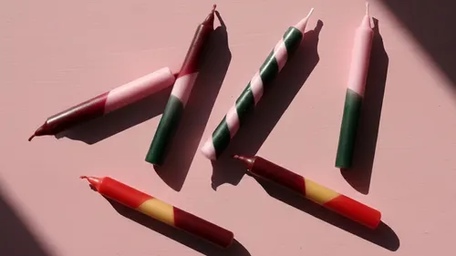 Colorful candles arranged on a pink surface.