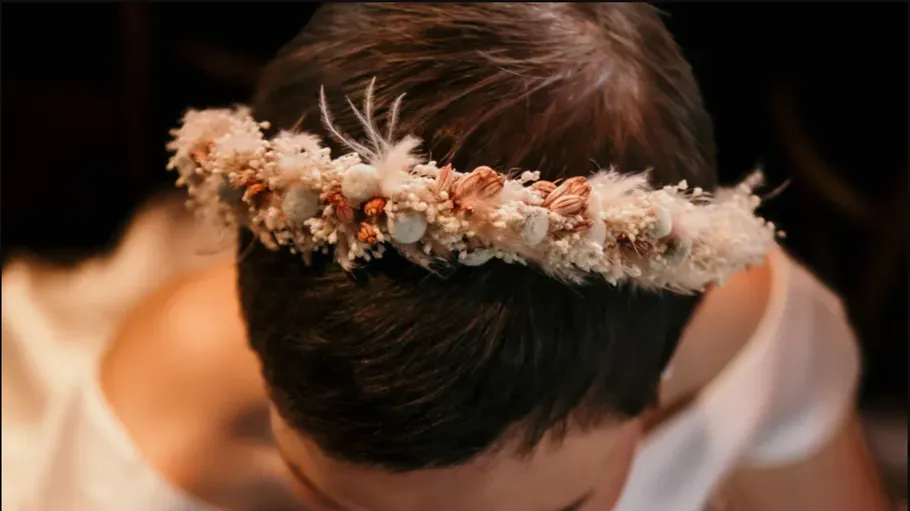 Person trägt Blumenkronen, schaut nach unten.