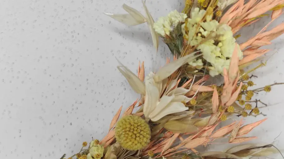Dried floral wreath on a white wall.