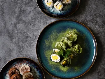 Grüner Sushi-Rollen, dekoriert mit pulverisiertem Tee, auf Tellern.