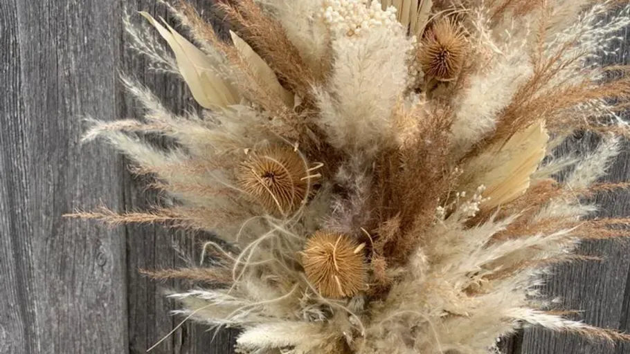 Dried floral arrangement against wooden background.