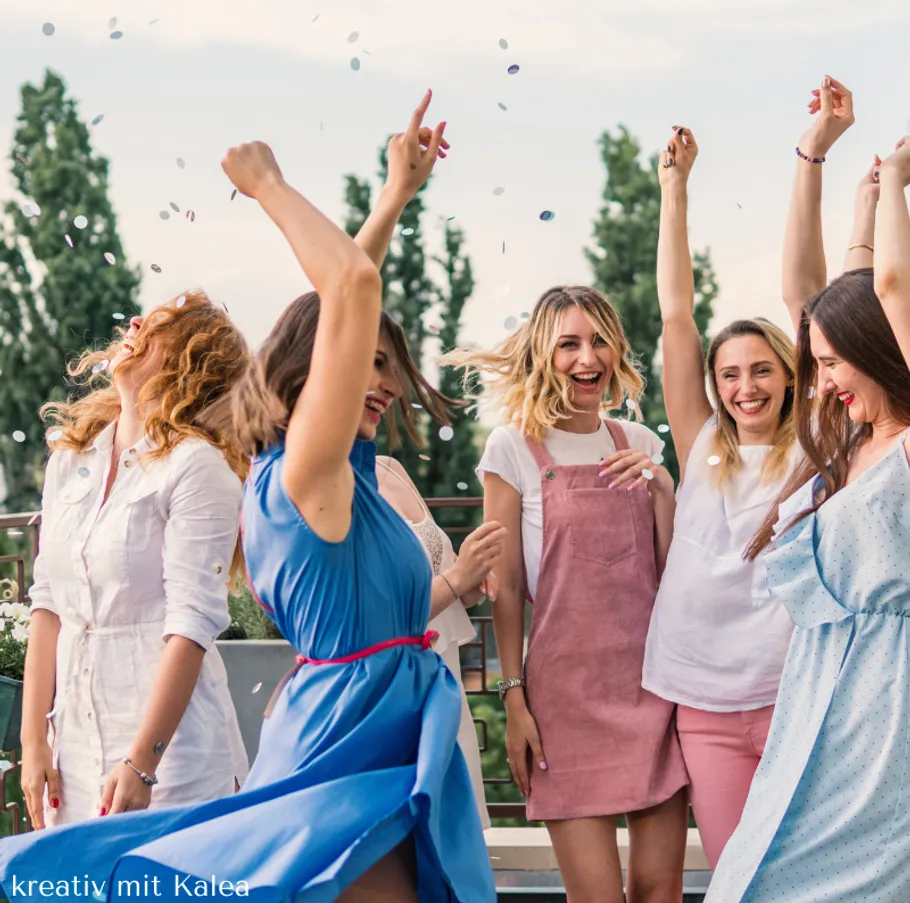 Frauen feiern mit Konfetti im Freien.