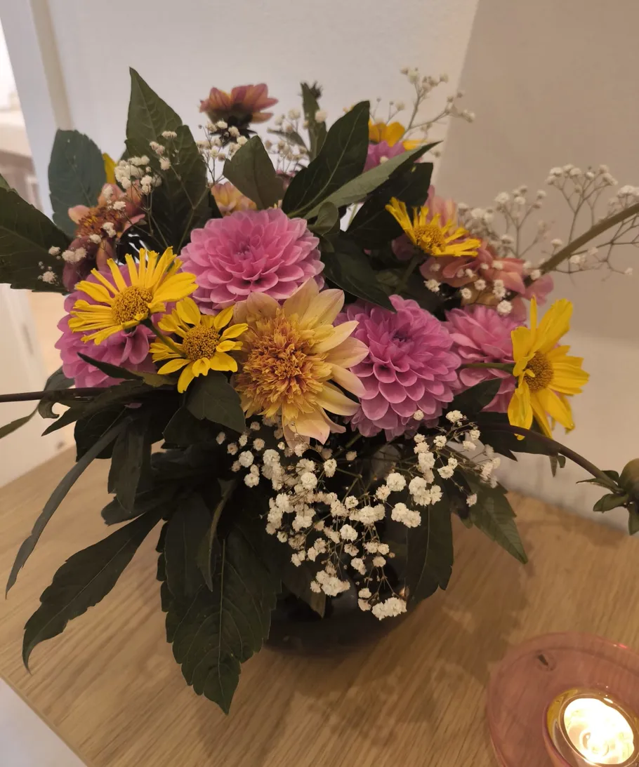 Bunte Blumen in einer Vase auf einem Tisch.