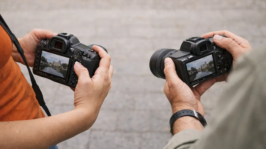 Two people holding cameras outdoors.