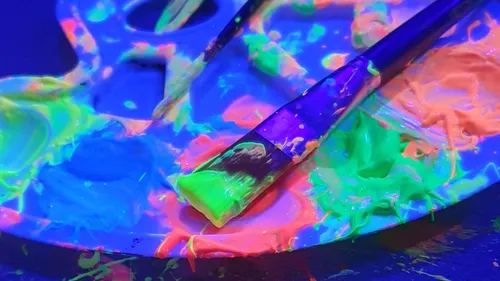 Pinsel auf Palette mit leuchtender Neonfarbe.