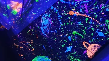 Farbenfrohes abstraktes Gemälde unter Schwarzlicht.