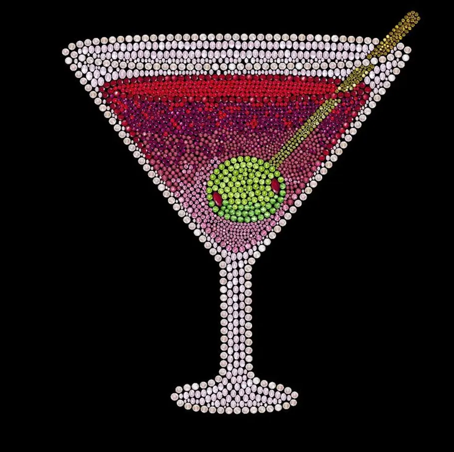 Beaded martini glass with olive, black background.