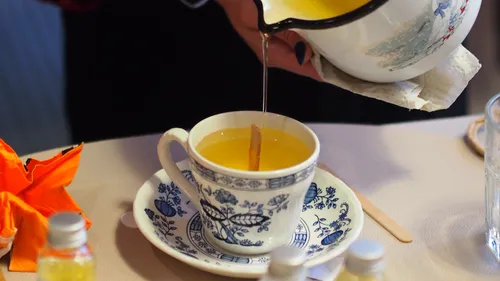 Tee wird in dekorierte Tasse auf Tisch gegossen.