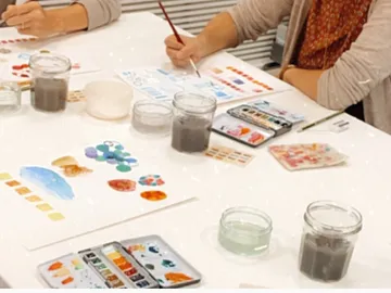 Wassertöpfe und Pinsel auf einem Tisch; Malen mit Aquarellen.