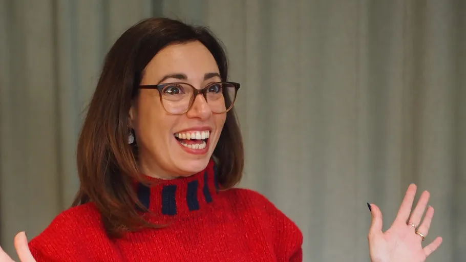 Woman smiling with raised hands indoors.