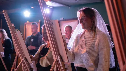 Women painting on easels in a studio.
