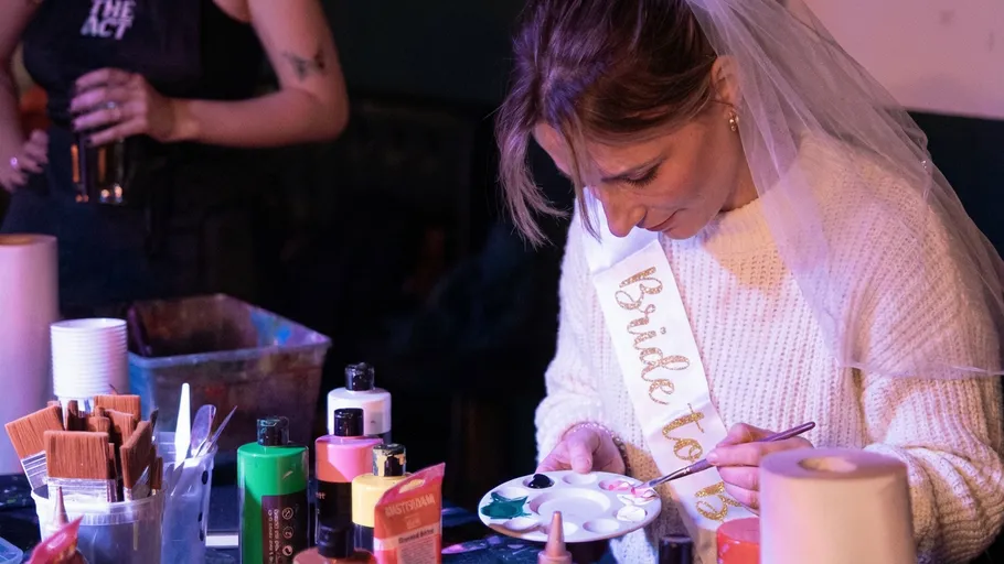 Woman painting at a party, wearing a veil.