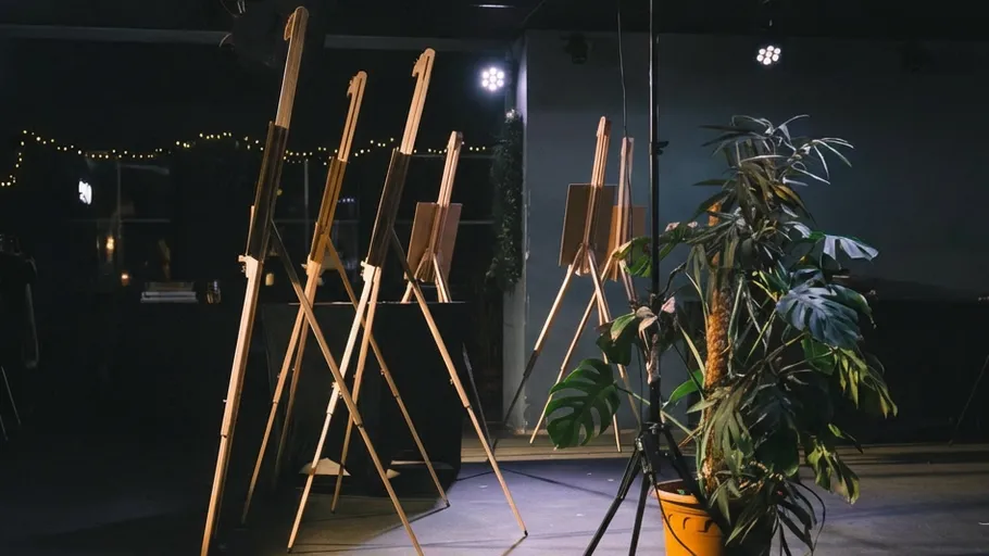 Easels lined up on stage beside a plant.