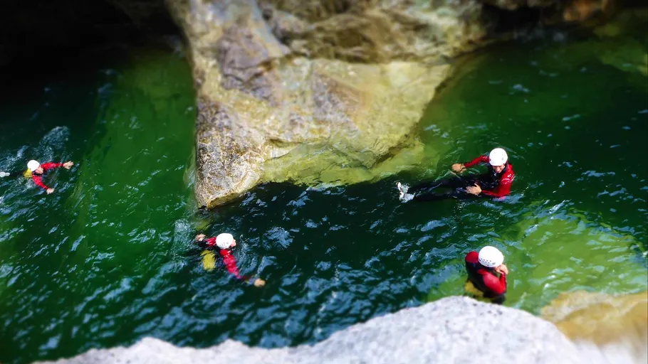 Four people canyoning in green water.