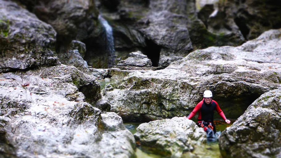 Person macht Canyoning durch felsiges Bachbett.