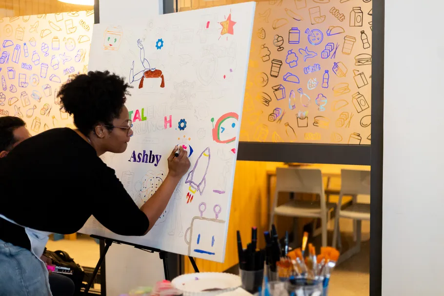 Frau zeichnet bunte Illustrationen auf Tafel.